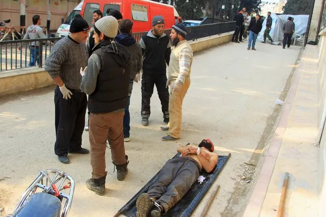 People stand near the body of a man, who died during what activists said were airstrikes carried out by the Russian air force in Idlib city, Syria December 20, 2015. (Photo by Ammar Abdullah/Reuters)