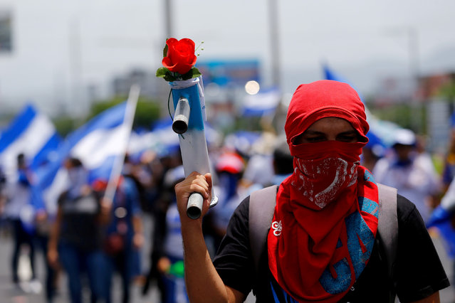 A masked demonstrator holds a homemade mortar with a flower during a march to demand the release of the political prisoners arrested during recent protests against Nicaragua's President Daniel Ortega's government in Managua, Nicaragua July 21, 2018. (Photo by Oswaldo Rivas/Reuters)