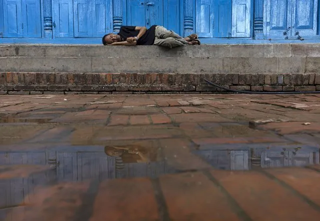 A man is reflected in the water as he sleeps on the street in Kathmandu, Nepal, 27 June 2023. Despite the Meteorological Forecasting Division of Nepal already announcing the onset of the monsoon season in the country on June 14, 2023, the monsoon rainfall has not been significantly active yet. (Photo by Narendra Shrestha/EPA)