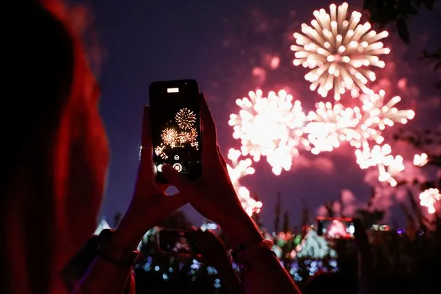 A fan of the K-pop boy band BTS takes pictures of fireworks during BTS 10th Anniversary FESTA in Seoul, South Korea on June 17, 2023. (Photo by Kim Soo-hyeon/Reuters)