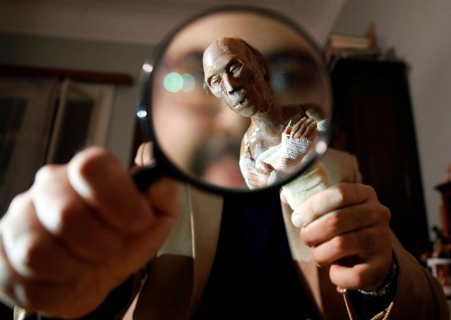 Fadi Francis, a 29-year-old journalist and artist, holds a magnifying glass and a white ceramic paste character of the mummy of ancient Egyptian King Ramses II that he made, in Cairo, Egypt on December 12, 2020. (Photo by Mohamed Abd El Ghany/Reuters)