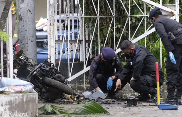 Members of a police bomb squad inspect the wreckage of a motorbike used to carry out Sunday's suicide bomb attack at the Sacred Heart of Jesus Cathedral in Makassar, South Sulawesi, Indonesia, Monday, March 29, 2021. Two attackers believed to be members of a militant network that pledged allegiance to the Islamic State group blew themselves up outside the packed Roman Catholic cathedral during a Palm Sunday Mass on Indonesia's Sulawesi island, wounding a number of people, police said. (Photo by Masyudi S. Firmansyah/AP Photo)