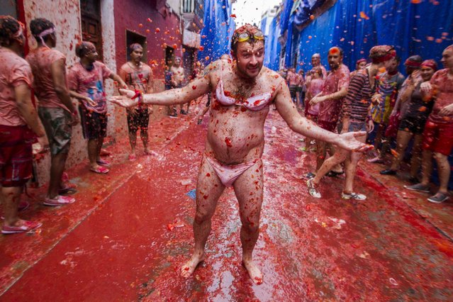 A man dressed in women's underwear enjoys a “tomato shower” during the traditional tomato fight “Tomatina” festival in Bunol, Spain, 28 August 2013. Bunol's city hall has sold 15,000 tickets to foreigners and with 5,000 residents, who don't have to pay, a total of 20,000 people have over 130,000 kg tomatoes to throw. Local authorities decided to sell tickets this year to avoid the traditional overcrowding of previous years in which over 50,000 people took part in the event. (Photo by Biel Alino/EPA)