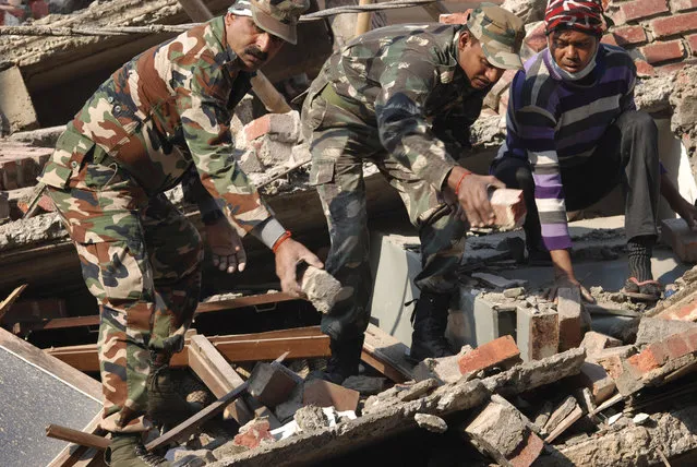 Indian soldiers and locals remove debris from a damaged building after an earthquake in Imphal, capital of the northeastern Indian state of Manipur, Monday, January 4, 2016. A 6.7 magnitude earthquake hit India's remote northeast region before dawn on Monday. (Photo by Bullu Raj/AP Photo)