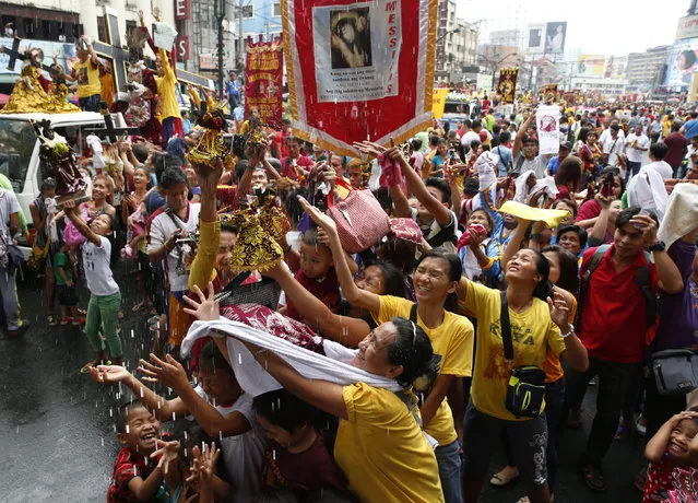 Devotees are sprinkled with holy water during a procession of Black Nazarene replicas two days before the annual procession of the Black Nazarene in Manila, Philippines January 7, 2016. (Photo by Erik De Castro/Reuters)
