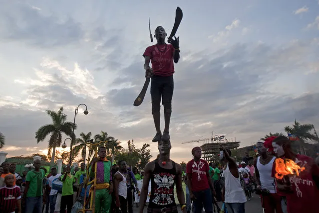 A performer juggles machetes while standing on top of his partner's head during Carnival celebrations in Port-au-Prince, Haiti, Monday, February 16, 2015. (Photo by Dieu Nalio Chery/AP Photo)