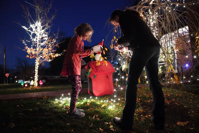 Juliette Haynie, 8, left center, stands by as her mother, Jeannette Haynie works on a strand of lights as she decorates outside their home on Thursday December 01, 2016 in Alexandria, VA. (Photo by Matt McClain/The Washington Post)