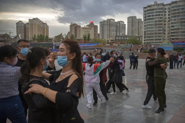 People dance to music at a public square in Aksu in western China's Xinjiang Uyghur Autonomous Region, as seen during a government organized trip for foreign journalists, Tuesday, April 20, 2021. (Photo by Mark Schiefelbein/AP Photo)