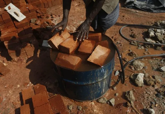 A man puts bricks into an oil barrel filled with water at a construction site in Colombo February 10, 2015. (Photo by Dinuka Liyanawatte/Reuters)