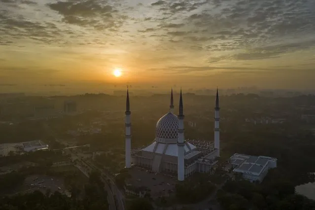 The sun rises behind the Sultan Salahuddin Abdul Aziz Mosque in Shah Alam on the outskirts of Kuala Lumpur, Malaysia, Sunday, July 16, 2023. (Photo by Vincent Thian/AP Photo)