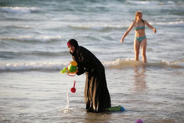A Muslim woman wearing a Hijab stands in the waters in the Mediterranean Sea as an Israeli stands nearby on the beach in Tel Aviv, Israel August 21, 2016. (Photo by Baz Ratner/Reuters)