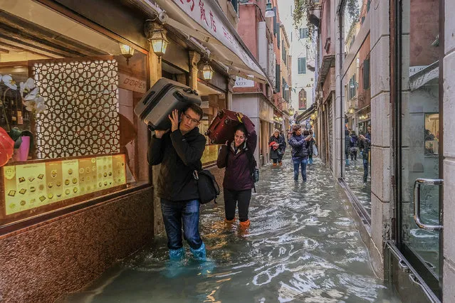 Tourists walk with their luggage in a side street in Venice on October 29, 2018 in Venice, Italy. (Photo by Stefano Mazzola/Awakening/Getty Images)