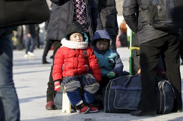 Jiang Rui (L), 4, his cousin Jiang Zixian, 5, and their grandparents wait for their train to hometown Anqing of Anhui province, at Beijing Railway station, in Beijing, China, January 25, 2016. (Photo by Jason Lee/Reuters)