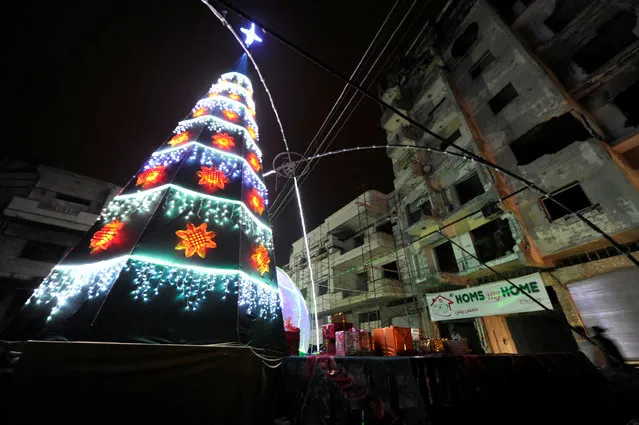 A Christmas tree lights near damaged buildings during Christmas eve in al-Hamidiyah neighbourhood in the old city of Homs, Syria December 24, 2016. (Photo by Omar Sanadiki/Reuters)
