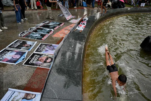 A child swims in a fountain as protesters display photos of Martial Law victims during a protest commemorating the 51st anniversary of the imposition of Martial Law, at Liwasang Bonifacio in Manila on September 21, 2023. (Photo by Jam Sta Rosa/AFP Photo)