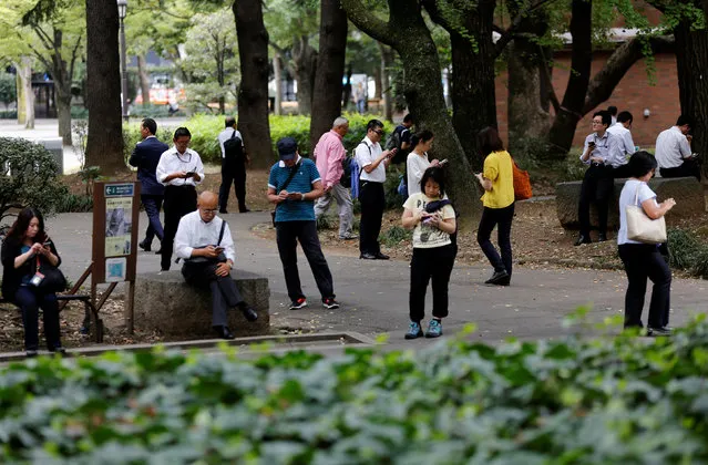 People stand with their mobile phones as some play Pokemon Go at a park in Tokyo, Japan, September 30, 2016. (Photo by Toru Hanai/Reuters)