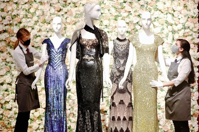 Gallery assistants handle a selection of dresses, including a gold sequined gown (right) worn by Penelope Cruz, amongst other items on display at Christie's in London, from the archive of fashion designer L'Wren Scott before it is offered at auction on Thursday, June 10, 2021. (Photo by Jonathan Brady/PA Images via Getty Images)