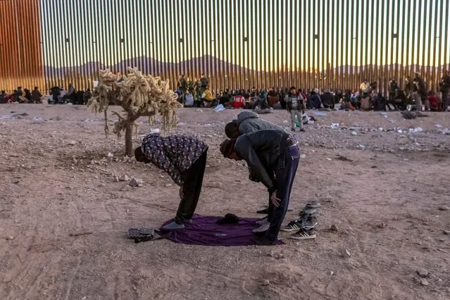 Immigrants from Senegal take part in a Muslim prayer at sunset while waiting with other migrants to be transported from the U.S.-Mexico border on December 06, 2023 in Lukeville, Arizona. A surge of immigrants illegally passing through openings cut by smugglers in the border wall has overwhelmed U.S. immigration authorities, causing them to shut down the international port of entry in Lukeville, so that officers can help process the new arrivals. (Photo by John Moore/Getty Images)
