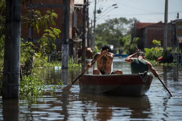 Men row on a boat along a flooded street in Vila Velha, Espirito Santo state, Brazil, on December 27, 2013. At least 44 people have died and more than 60,000 have been left homeless following torrential rains over the past few weeks in southeast Brazil. (Photo by Yasuyoshi Chiba/AFP Photo)