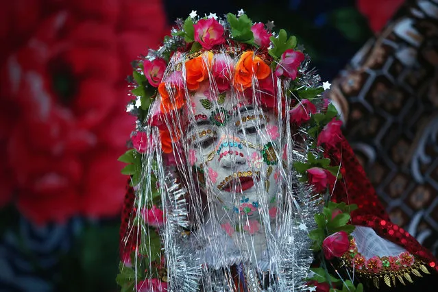 Bride Fatme Inus, her face painted white and decorated with sequins, emerges to present herself to villagers towards the end of her two-day wedding to Mustafa Sirakov on January 12, 2014 in Ribnovo, Bulgaria. (Photo by Sean Gallup/Getty Images)