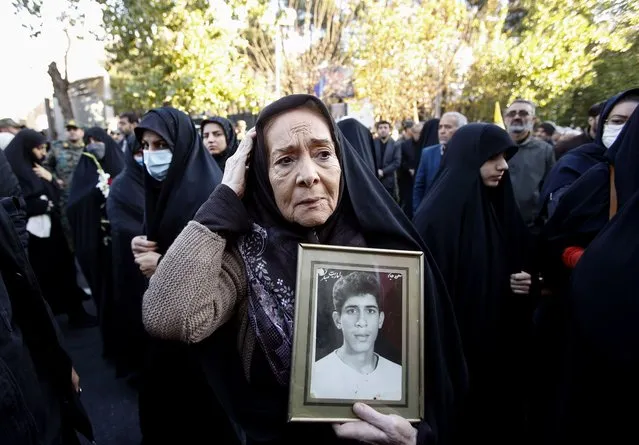 An elderly Iranian woman holds a picture of her son who went missing in the Iran-Iraq war during a ceremony marking the return of remains of Iranian soldiers killed in the Iran-Iraq war, in Tehran, Iran on December 17, 2023. According to the IRNA News Agency, some 110 bodies of soldiers killed in the Iran-Iraq war that lasted from 1980 to 1988 were discovered recently in Iraq. Hundreds of thousands of Iranians are thought to have been either killed or went missing during the conflict, with some of their bodies found in recent years. (Photo by Abedin Taherkenareh/EPA/EFE)