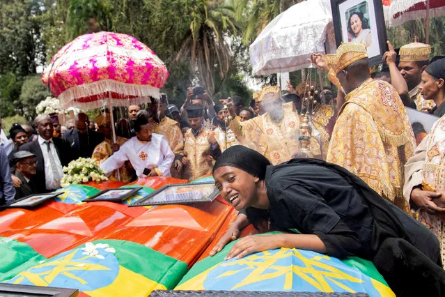 A woman mourns next to coffins during the burial ceremony of the Ethiopian Airline Flight ET 302 crash victims at the Holy Trinity Cathedral Orthodox church in Addis Ababa, Ethiopia, March 17, 2019. Thousands of Ethiopians have turned out to a mass funeral ceremony in the capital one week after the Ethiopian Airlines plane crash. Officials have begun delivering bags of earth to family members of the 157 victims of the crash instead of the remains of their loved ones because the identification process is going to take such a long time. (Photo by Maheder Haileselassie/Reuters)