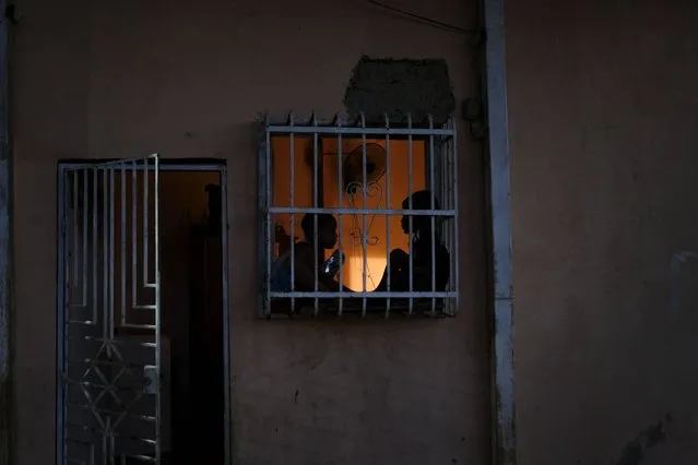 Children talk to each other sitting on a window at their home in the Catia neighborhood of Caracas, Venezuela, Monday, September 20, 2021. (Photo by Matias Delacroix/AP Photo)