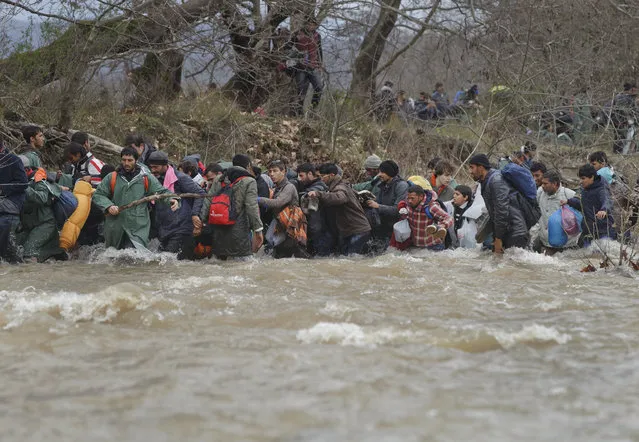Migrants cross a river, north of Idomeni, Greece, attempting to reach Macedonia on a route that would bypass the border fence, Monday, March 14, 2016. (Photo by Vadim Ghirda/AP Photo)