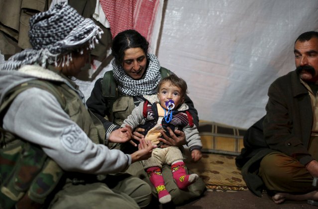 Female Kurdistan Workers Party (PKK) fighters sit with a Yazidi family, including a member of YBS (R), near their base in Sinjar, March 12, 2015. YBS are a Yazidi militant group, who are fighting against Islamic State. (Photo by Asmaa Waguih/Reuters)