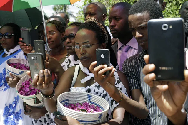 Friends and relatives of Jean Claude Niyonzima, who was killed during clashes with police over the move by President Pierre Nkurunziza to seek a third term in office, take pictures during his burial ceremony outside Bujumbura, Burundi, Saturday May 2, 2015. Many people have gathered in the streets over the past few days to protest against President Pierre Nkurunziza's decision to run for election as president for a third term in office. (Photo by Jerome Delay/AP Photo)
