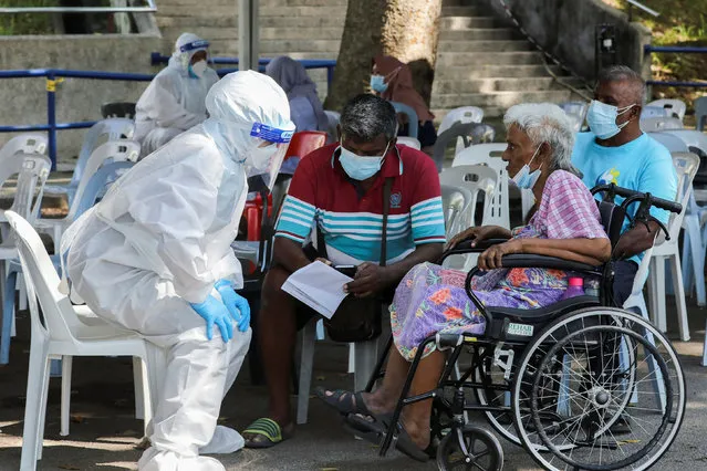 A medical worker wearing personal protective equipment (PPE) speaks to people outside a coronavirus disease (COVID-19) assessment centre, in Shah Alam, Malaysia on August 30, 2021. (Photo by Lim Huey Teng/Reuters)