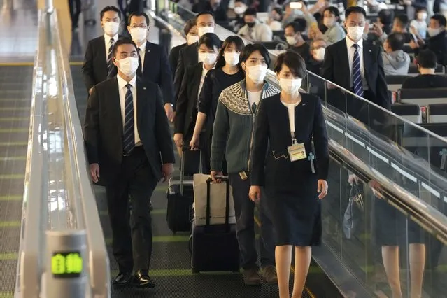 Japan's former Princess Mako, third right, the elder daughter of Crown Prince Akishino, and her husband Kei Komuro, second right, are escorted to board an airplane to New York Sunday, November 14, 2021, at Tokyo International Airport in Tokyo. (Photo by Eugene Hoshiko/AP Photo)