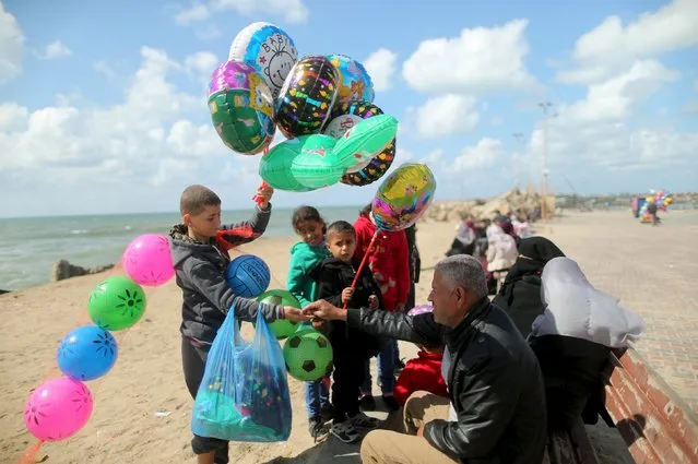 Palestinian boy Mahmoud al-Sindawi, 15, sells balloons and footballs at the Seaport of Gaza City March 17, 2016. Sindawi, whose father is unemployed, earns around 25 Shekels ($6.4) per working day and he and his brother are the main breadwinners of their family. He hopes to be a trader as he still goes to school. (Photo by Mohammed Salem/Reuters)
