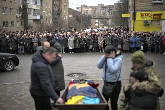 Bucha relatives gather to mourn the body of Oleksiy Zavadskyi, a Ukrainian serviceman who died in combat on January 15 in Bakhmut, during his funeral in Bucha, Ukraine, Thursday, January 19, 2023. (Photo by Daniel Cole/AP Photo)