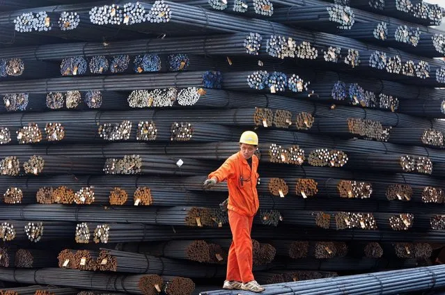 This picture taken on March 17, 2014 shows a worker walking on steel rods in a steel market in Qingdao, in eastern China's Shandong province. Foreign direct investment (FDI) into China increased 10.4 percent in the first two months of 2014 from last year, the government said on March 18, while the country's outbound investment slumped. (Photo by AFP Photo)