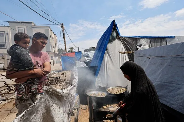 A displaced Palestinian family makes traditional cakes as they prepare for the Eid al-Fitr holiday at a tent camp in Rafah, in the southern Gaza Strip on April 8, 2024. (Photo by Mohammed Salem/Reuters)