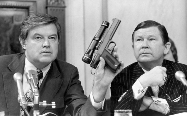 Chairman Frank Church, D-Idaho, of the Senate Intelligence Committee, displays a poison dart gun Sept.17,1975 as Co-Chairman John G. Tower, R-Texas, looks at the weapon during the panels probe of the Central Intelligence Agency at a Washington hearing. The committe also heard from CIA Director William E. Colby, who told them that 37 lethal poison were discovered in an agency lab. (Photo by hlg/AP Photo)