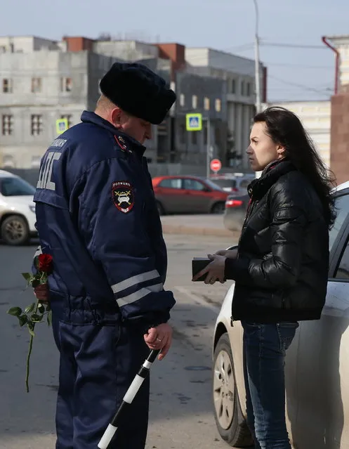 A traffic policeman congratulates a female driver on upcoming International Women's Day in Ryazan, Russia on March 7, 2017. (Photo by Alexander Ryumin/TASS via Getty Images)