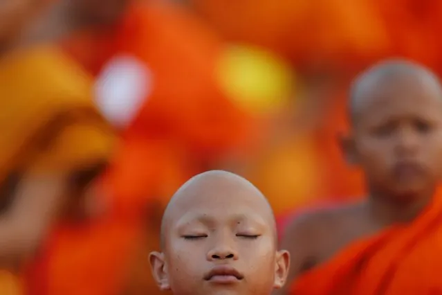 A Buddhist novice sleeps while monks gather to receive alms at Wat Phra Dhammakaya temple, in what organizers said was a meeting of over 100,000 monks, in Pathum Thani, outside Bangkok April 22, 2016. (Photo by Jorge Silva/Reuters)