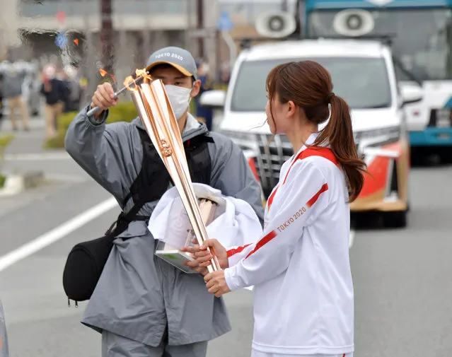 A staff member reignite the torch during first day of the Tokyo 2020 Olympic torch relay in Tomioka, Fukushima prefecture, Japan, 25 March 2021. The postponed Tokyo 2020 Olympic Games are scheduled to start on 23 July 2021 and some 10,000 torchbearers will run across the country along a 121-day journey. (Photo by Japan Pool/EPA/EFE)