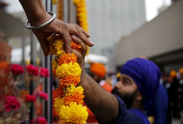 A Sikh man hands garlands of carnations to another during Khalsa Day festivities, also known as Vaisakhi, in front of city hall in Toronto, Canada April 24, 2016. (Photo by Chris Helgren/Reuters)