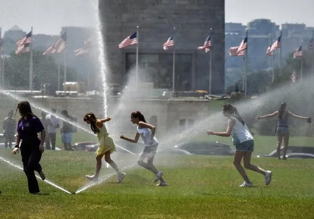 Visitors take a run through a sprinkler on the Mall during another day of triple-digit heat in Washington, D.C. on July 21, 2019. (Photo by Bill O'Leary/The Washington Post)