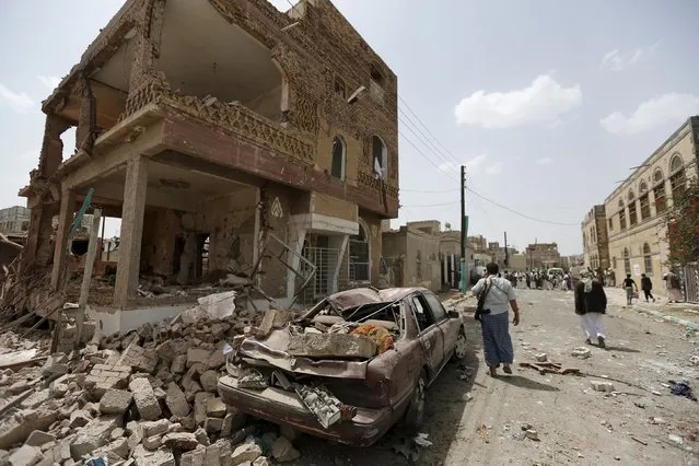 People walk at a site hit by a Saudi-led air strike in Yemen's capital Sanaa July 3, 2015. Warplanes from a Saudi-led coalition bombed targets in the Yemeni capital on Friday, residents said, and sources in the country's dominant Houthi militia reported at least six people including a woman and child were killed. (Photo by Khaled Abdullah/Reuters)