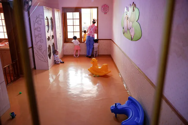 Children look through the window of the kindergarten of the Kim Jong Suk Pyongyang textile mill during a government organised visit for foreign reporters in Pyongyang, North Korea May 9, 2016. (Photo by Damir Sagolj/Reuters)