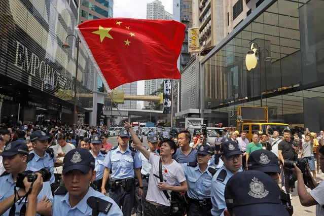 A pro-China supporter is escorted out of a shopping mall by police while waving a Chinese national flag in Hong Kong, Wednesday, September 18, 2019. Activists involved in the pro-democracy protests in Hong Kong appealed to U.S. lawmakers Tuesday to support their fight by banning the export of American police equipment that is used against demonstrators and by more closely monitoring Chinese efforts to undermine civil liberties in the city. (Photo by Kin Cheung/AP Photo)