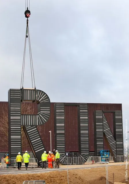 Workers carryout the installation of artist Monica Bonvicini's 'RUN' sculpture in the plaza of the London 2012 Handball Arena at the Olympic Park