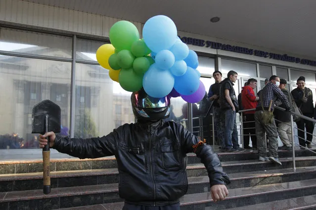 A man with balloons attached to his helmet poses for a picture as pro-Russian activists hold a rally near the headquarters of the regional interior ministry to demand the resignation of its head Anatoly Naumenko in Luhansk, eastern Ukraine, May 7, 2014. (Photo by Valentyn Ogirenko/Reuters)