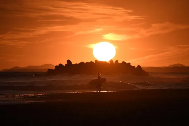 A surfer walks on the beach at sunset on September 19, 2019, at Nakatajima-Sakyu Dunes in Hamamatsu, Japan. (Photo by Anne-Christine Poujoulat/AFP Photo)