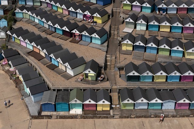 In this aerial view, a man sunbathes in front of a row of beach huts on June 26, 2024 in Walton-On-The-Naze, England. Brits are enjoying warmer temperatures this week, with highs reaching the low 30s in parts of the UK, peaking on Wednesday. (Photo by Dan Kitwood/Getty Images)