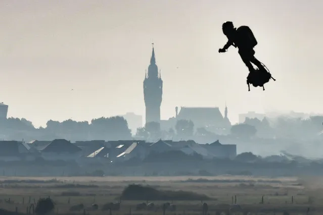 Franky Zapata on his jet-powered “flyboard” flies past the belfry of the city hall of Calais (C) after he took off from Sangatte, northern France, on August 4, 2019, during his attempt to fly across the 35-kilometre (22-mile) Channel crossing in 20 minutes, while keeping an average speed of 140 kilometres an hour (87 mph) at a height of 15-20 metres (50-65 feet) above the sea. Frenchman who has spent years developing a jet-powered hoverboard will again try to zoom across the English Channel on August 4, after a first attempt last month was cut short when a botched refuelling attempt sent him into the water. (Photo by Denis Charlet/AFP Photo)